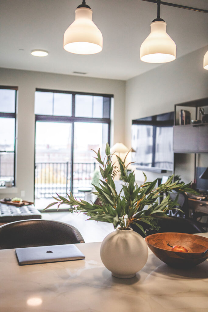 Spacious Pearl apartment living room with large windows, wood-style flooring, and city views in Fort Wayne